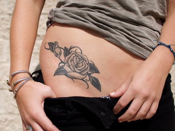 Middle size rose tattoo on the upper side of the right hip