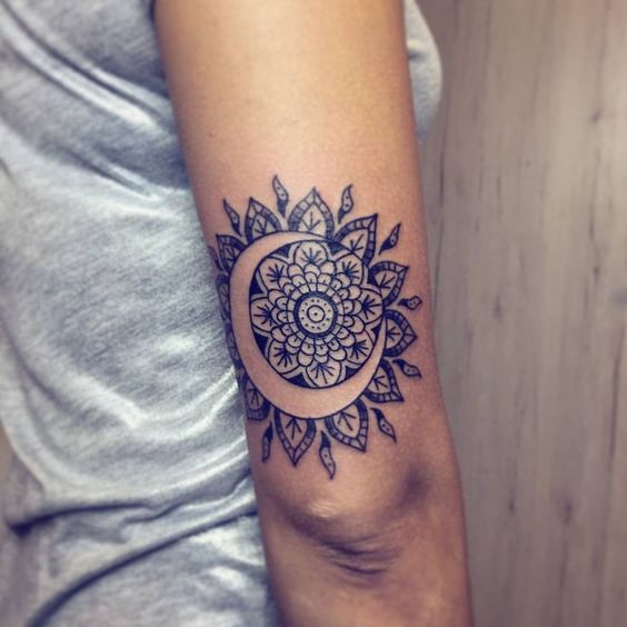 Negative space crescent moon and mandala sun tattoo on the back of the right upper arm