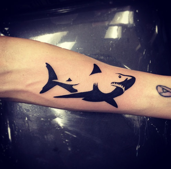 Negative space shark tattoo on the left inner arm