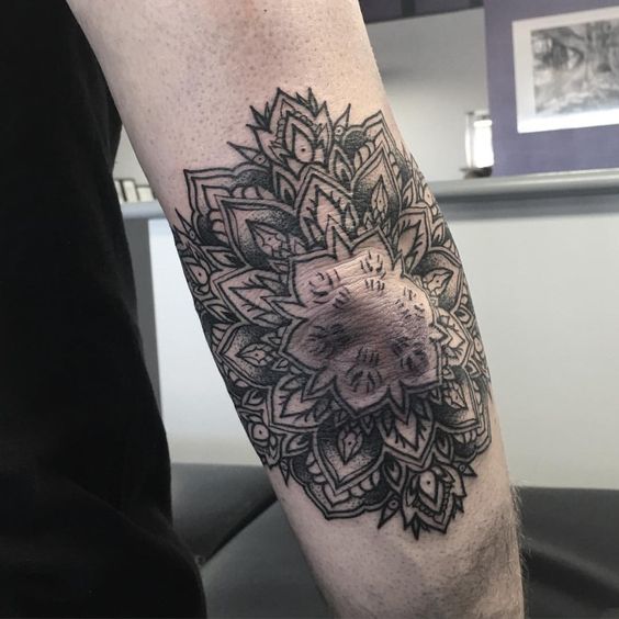 Outline black mandala tattoo on the right elbow