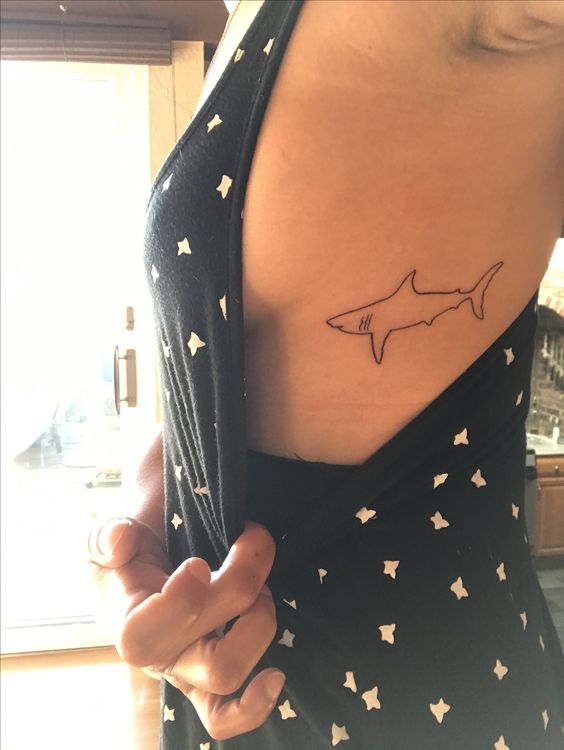 Outline tattoo of a shortfin mako shark on the left rib cage