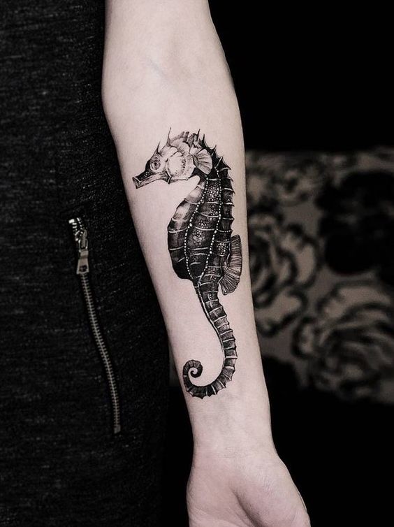 Realistic black seahorse tattoo on the left arm by diana severinenko
