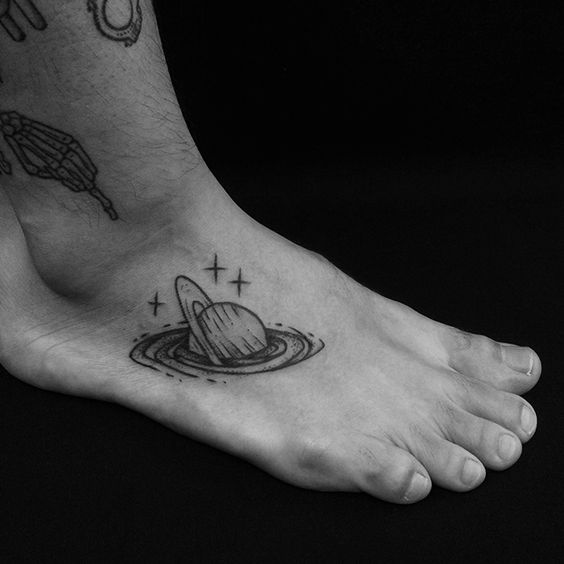 Saturn sinking in a blackhole tattoo on the right foot