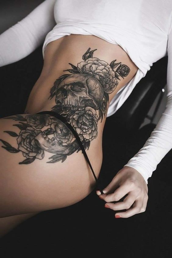 Skull and roses black tattoo on the left hip and thigh