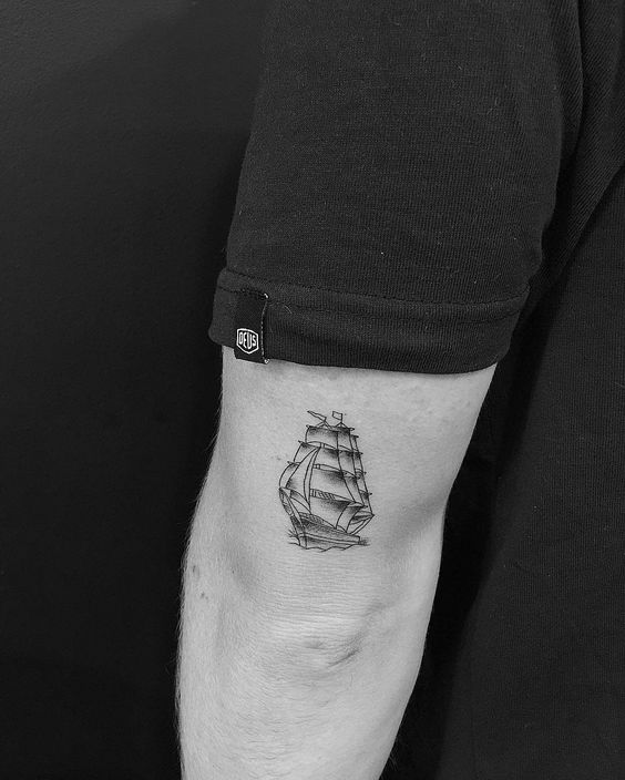 Small black ship tattoo on the back of the upper arm