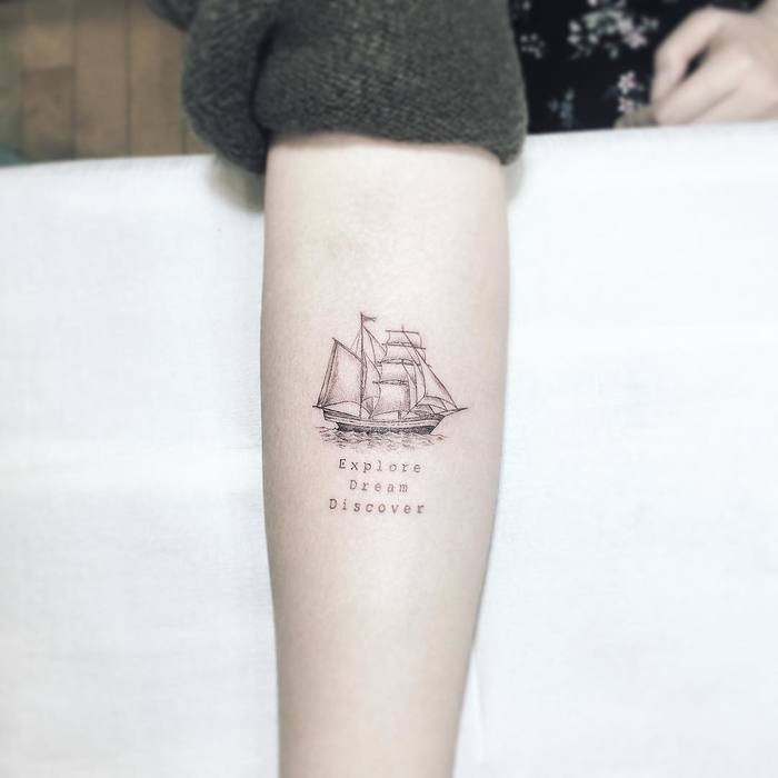 Small black ship tattoo with inspiring words explore dream discover