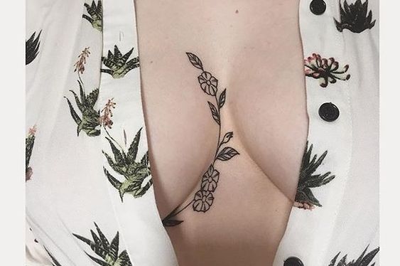 Small flower tattoo between the breasts