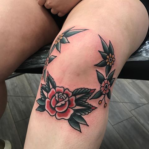 Small red traditional rose tattoo below the knee