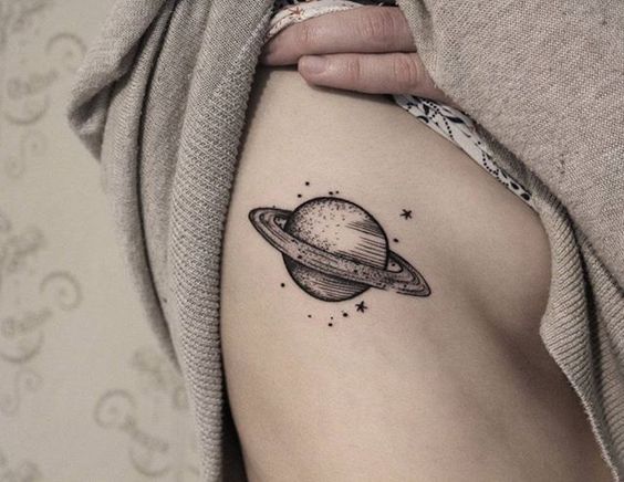 Tattoo of a black saturn on the right rib cage