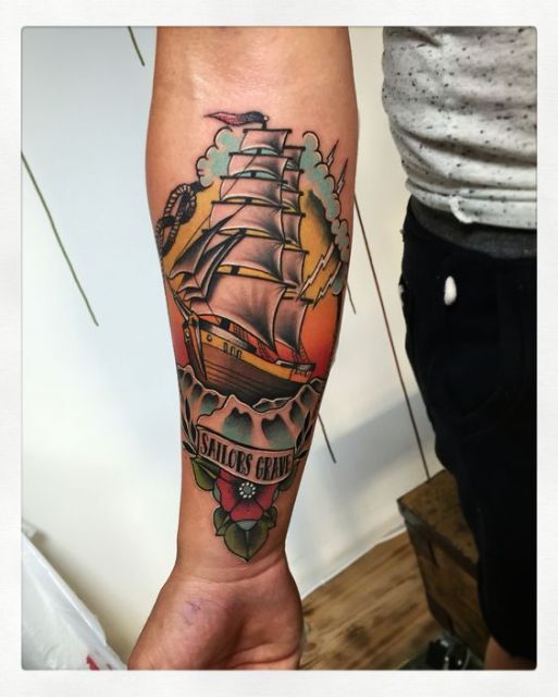 Tattoo of a ship on the right arm with the words sailors grave below
