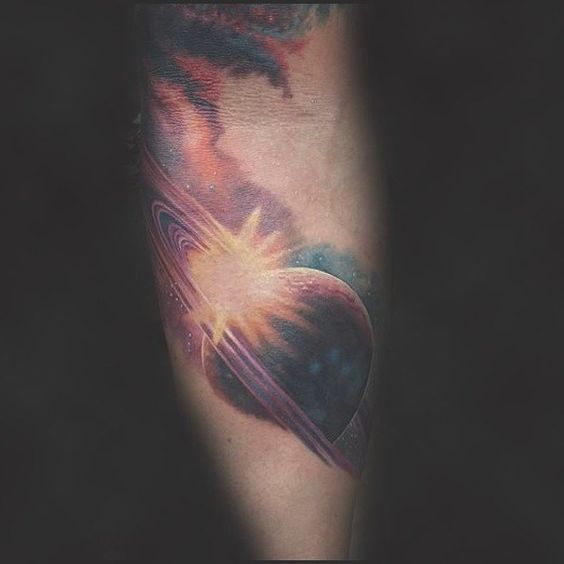 Tattoo of a sunburst over the planet saturn