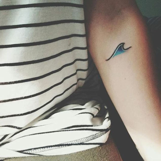 Tiny blue wave tattoo on the left inner arm