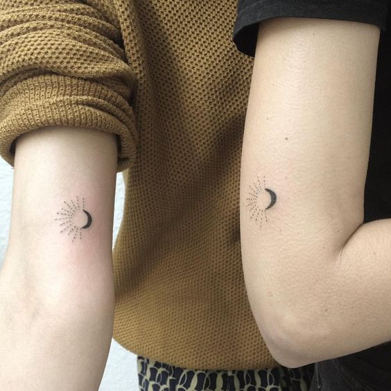 Tiny matching sun and moon tattoos on the arms