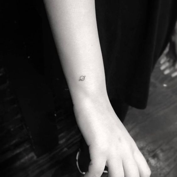 Tiny tattoo of saturn on the right wrist