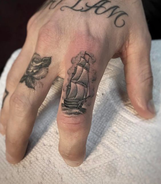 Tiny traditional ship tattoo on the index finger by ben grillo