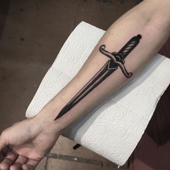 Traditional black dagger tattoo on the inner arm