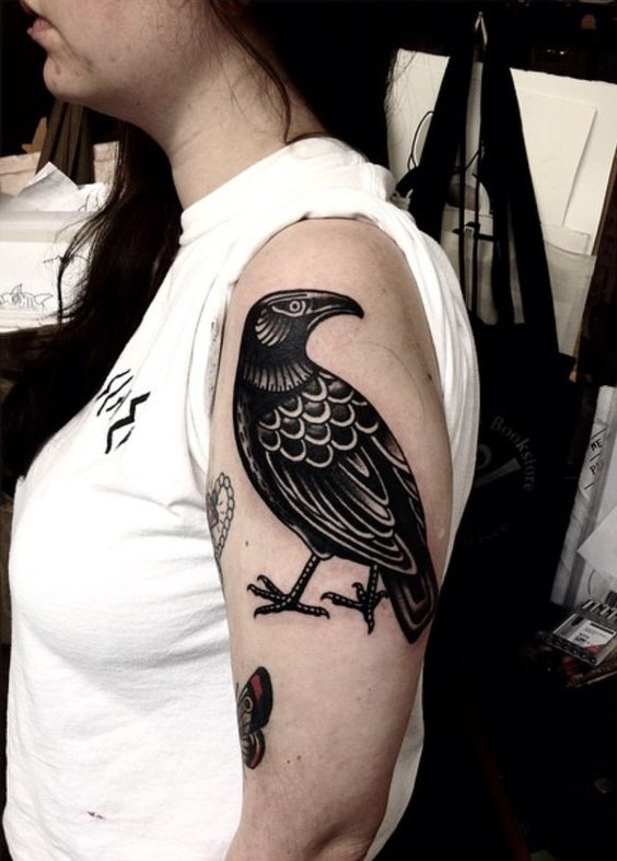 Traditional black raven tattoo on the left upper arm