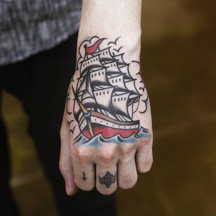 Traditional sailing ship tattoo on the left hand
