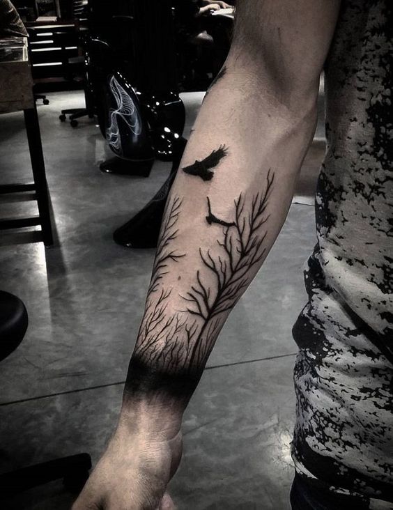 Two black ravens and trees tattoo on the right arm by cavera wolf