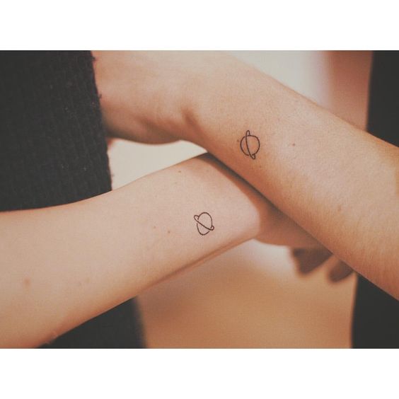 Two tiny saturn tattoos on both wrists