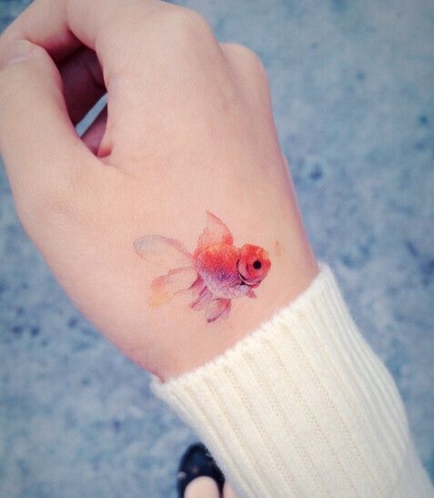 Watercolor goldfish tattoo on the hand