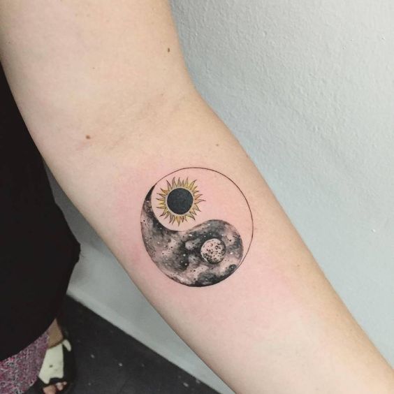 Yin and yang moon and sun tattoo on the arm