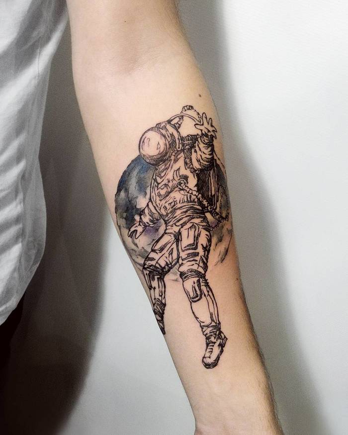 Astronaut and moon in the background tattoo on the left forearm
