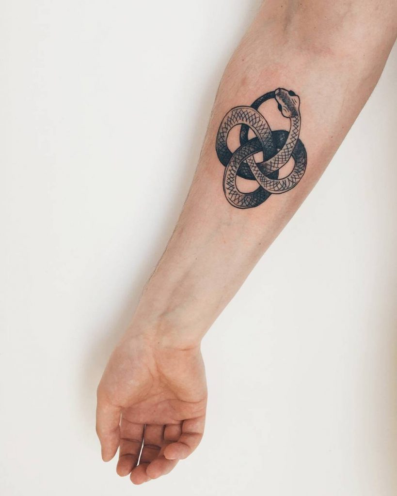 Black and grey ouroboros tattoo on the forearm