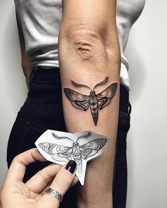 Black moth tattoo on the right forearm