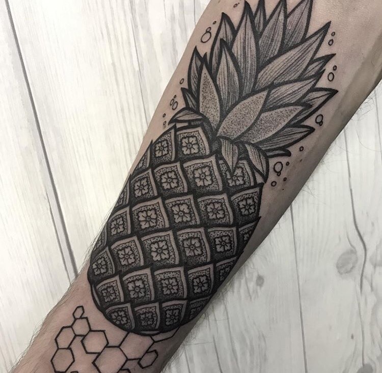Black ornamental pineapple tattoo on the arm
