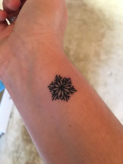 Black snowflake wrist tattoo