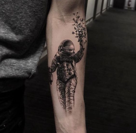 Cosmonaut holding a flower bouquet tattoo on the arm