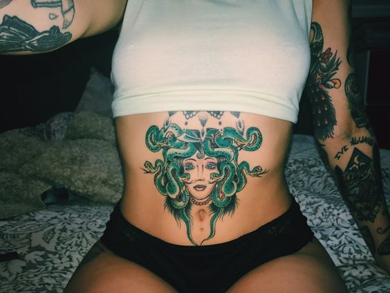 Green medusa head tattoo on the belly