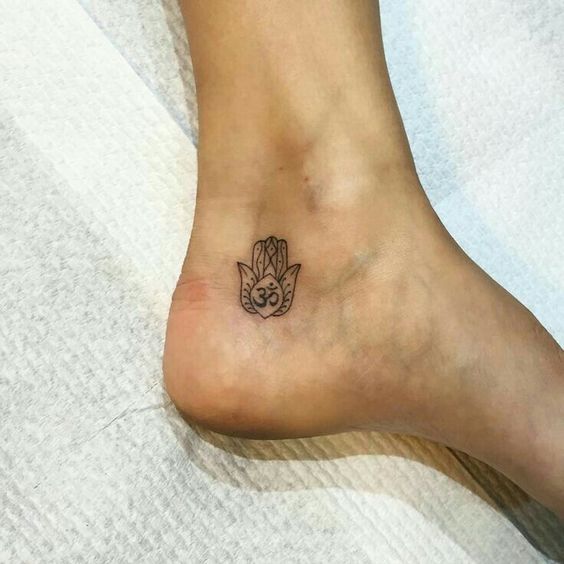 Hamsa hand and om tattoo on the left inner ankle