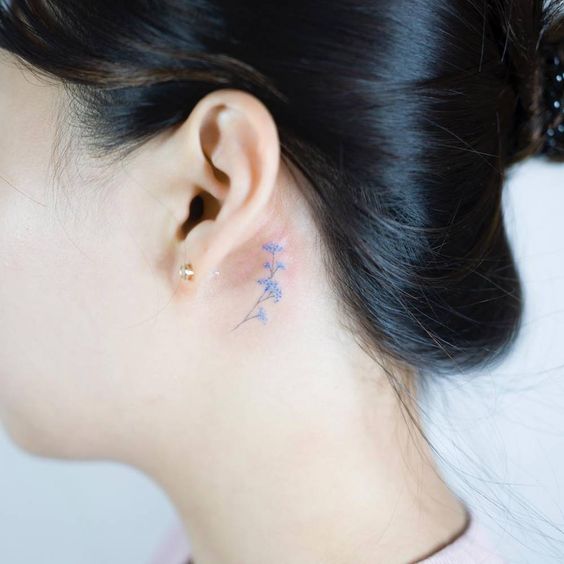 Incredibly tiny forget me not flower tattoo behind the ear