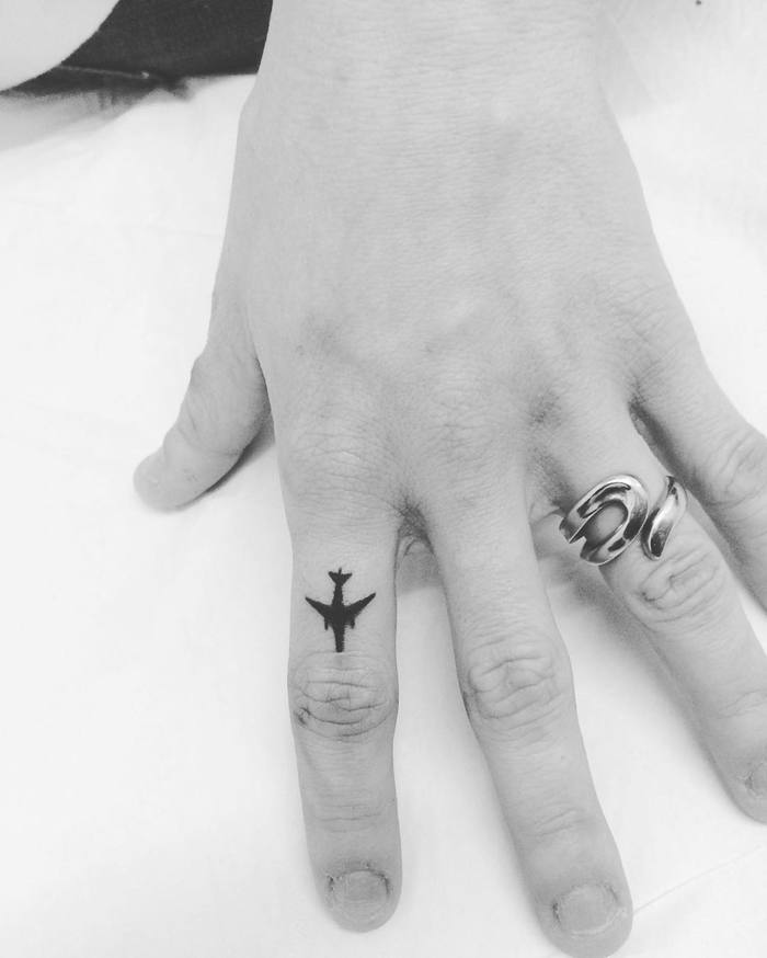 Little black plane tattoo on the index finger