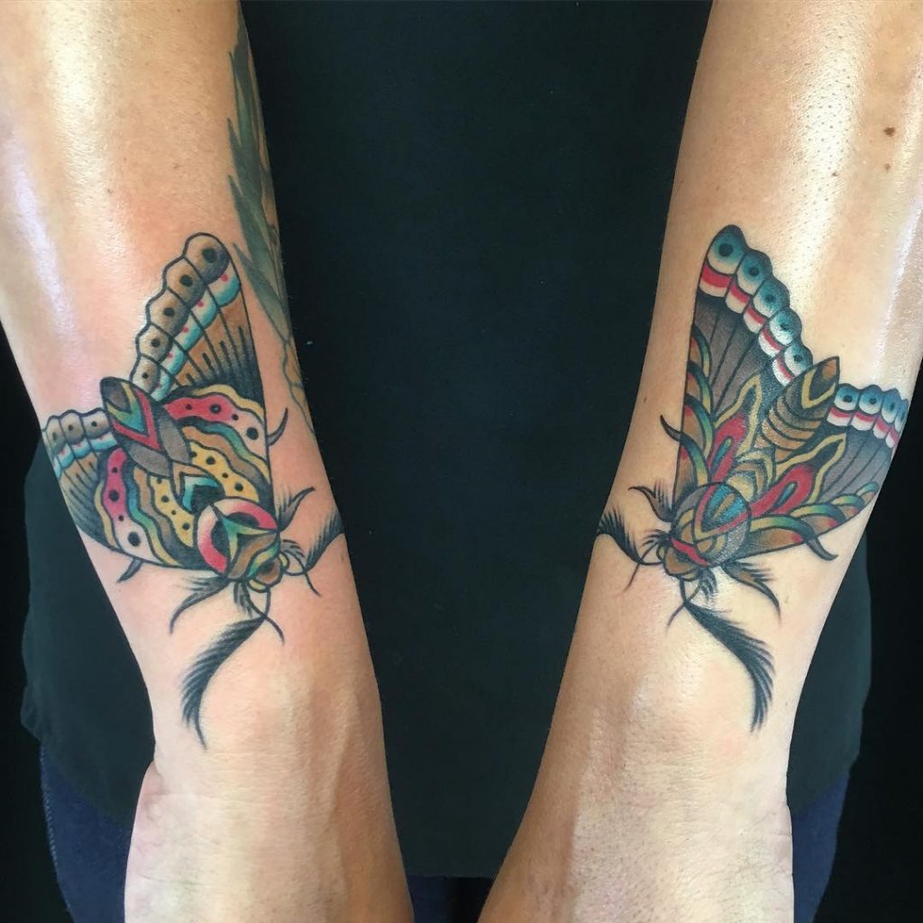 Matching moth tattoos on both forearms