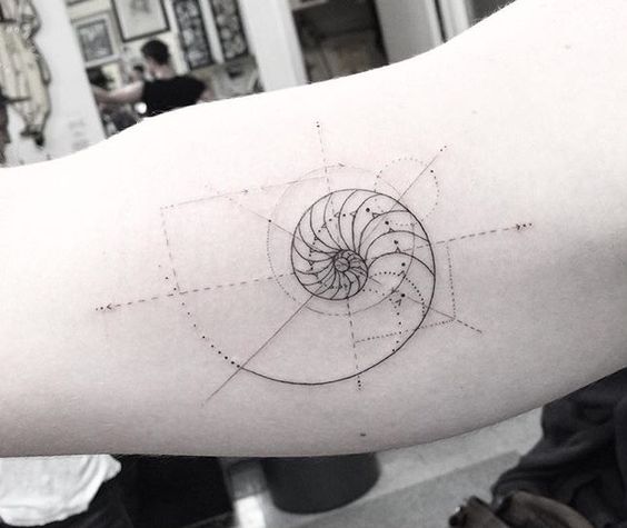 Minimalist style golden spiral tattoo on the arm