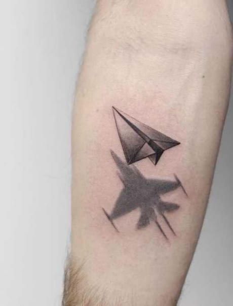 Paper plane and a shadow of the war jet aircraft tattoo on the arm