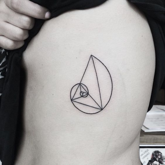 Simple golden spiral tattoo on the left rib cage