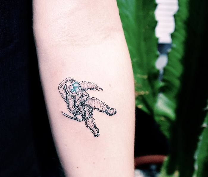 Small astronaut tattoo on the right arm