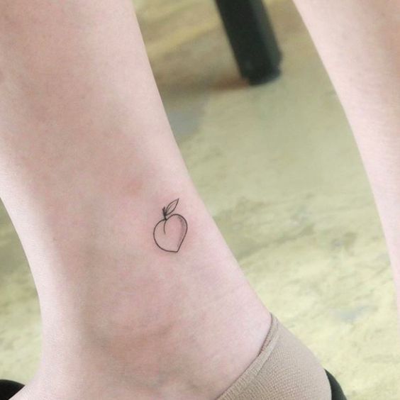 Small black and white peach tattoo on the ankle