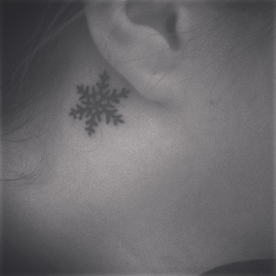 Small snowflake behind the ear tattoo