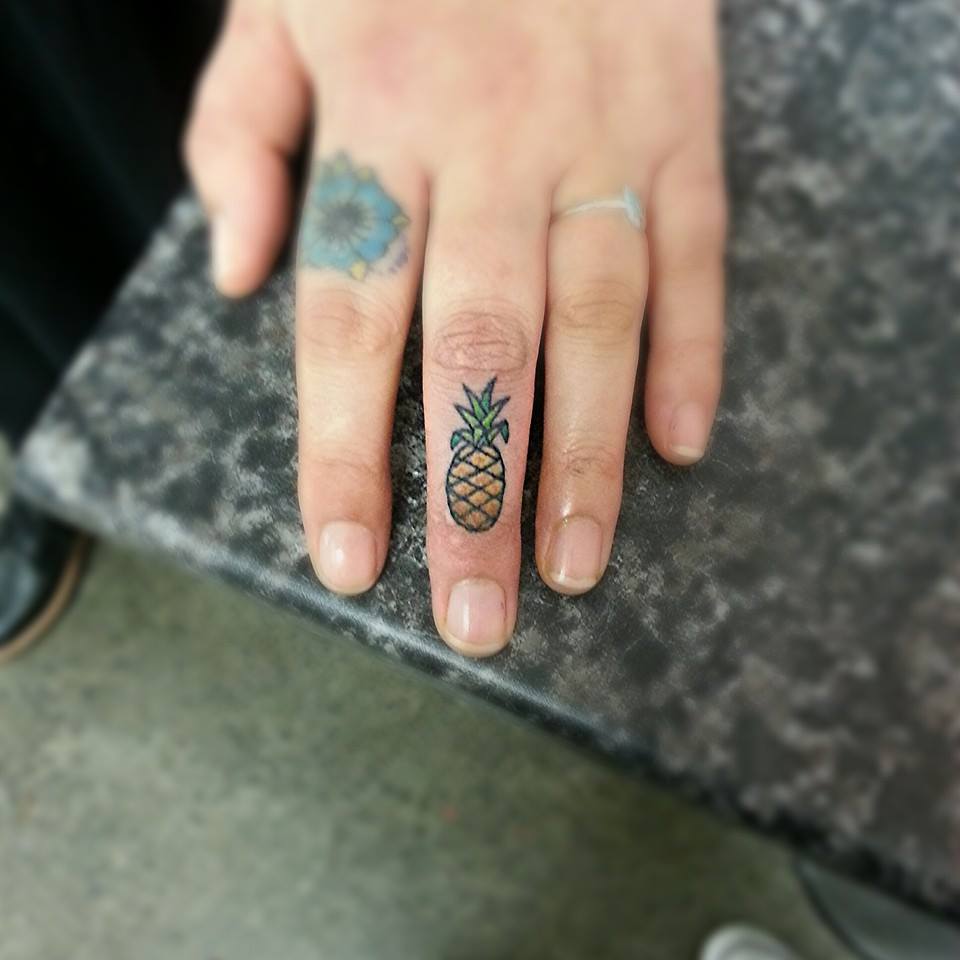 Tiny pineapple tattoo on the middle finger