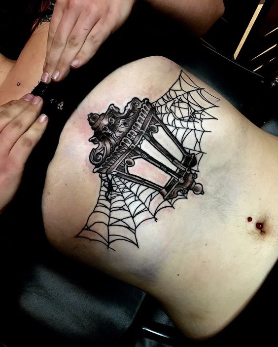 Victorian lantern and spiderweb tattoo on the sternum