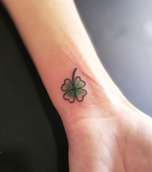 Black and green four leaf clover tattoo on the inner wrist