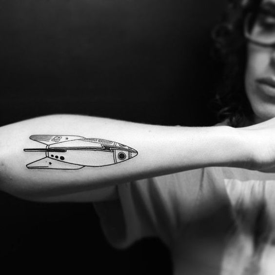 Black spaceship tattoo on the right forearm