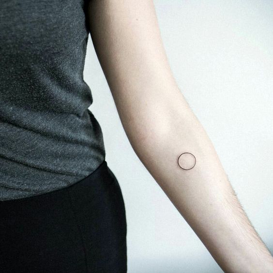 Minimal circle tattoo on the left inner forearm