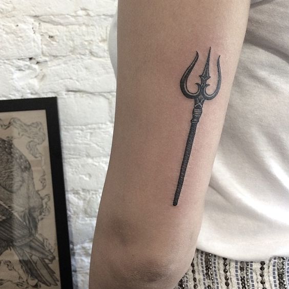 Small trident tattoo on the back of the left upper arm