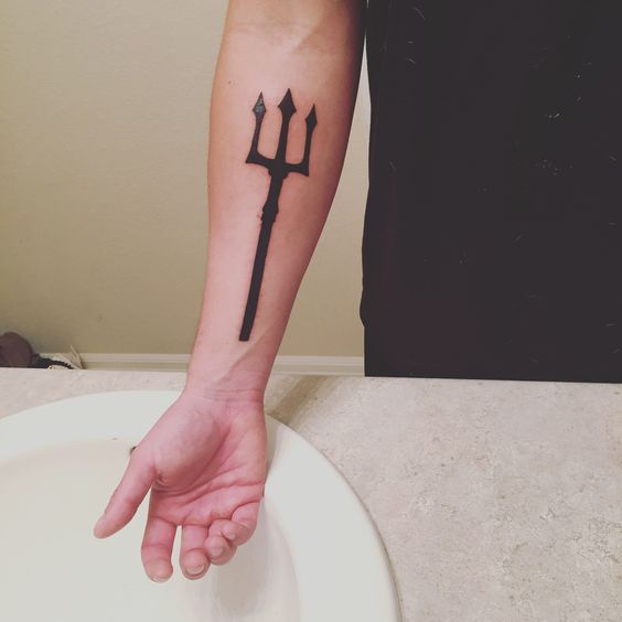 Solid black trident tattoo on the inner forearm